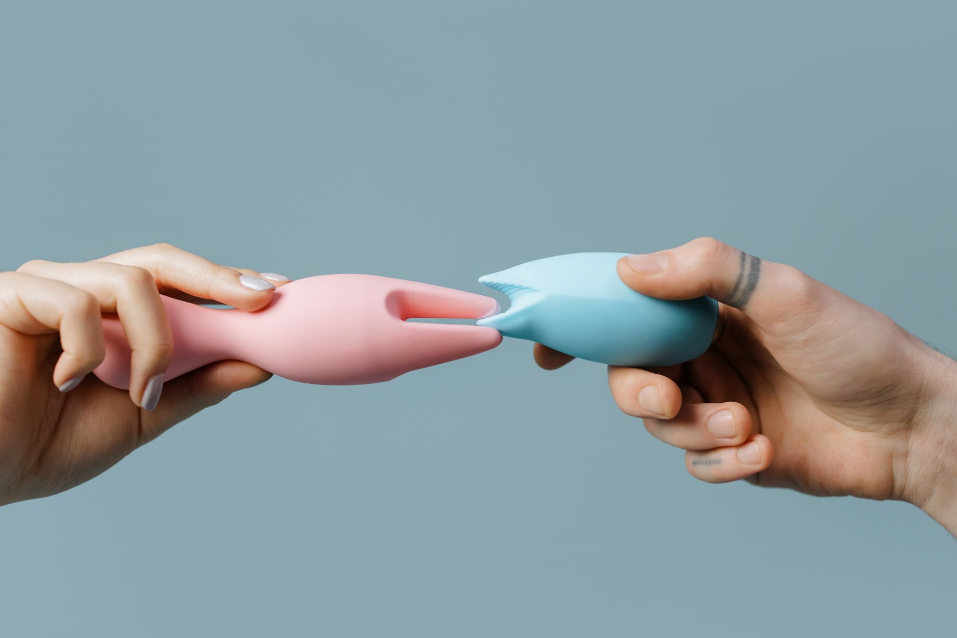 A couple holding a blue vibrator together, representing modern intimacy and shared pleasure